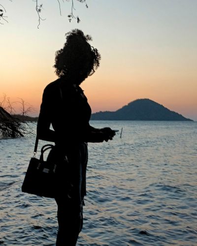 Faith Zulu, a young staffer at TWR partner One Love Radio in Zambia, is silhouetted against the backdrop of Lake Malawi.