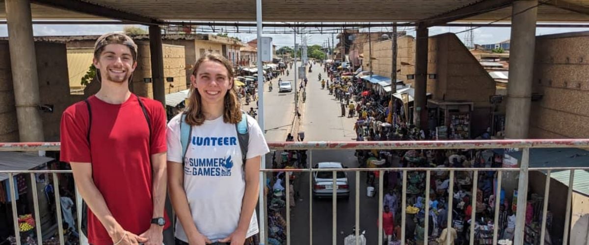 Elizabeth (right) and Luke (left), fellow interns serving in West Africa, smile for the camera overlooking an African street. 