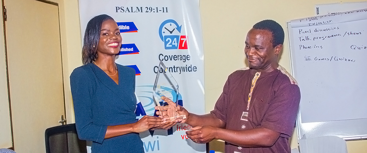 Janet recieving the award from Victor A man and a woman holding an award.