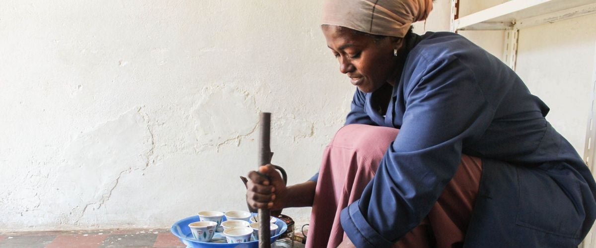 An Ethiopian woman crouches on the ground using tools