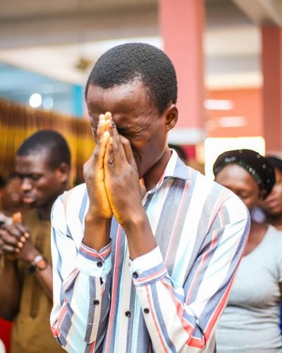 A man prays with hands clasped before his face in a church in Nigeria. 
