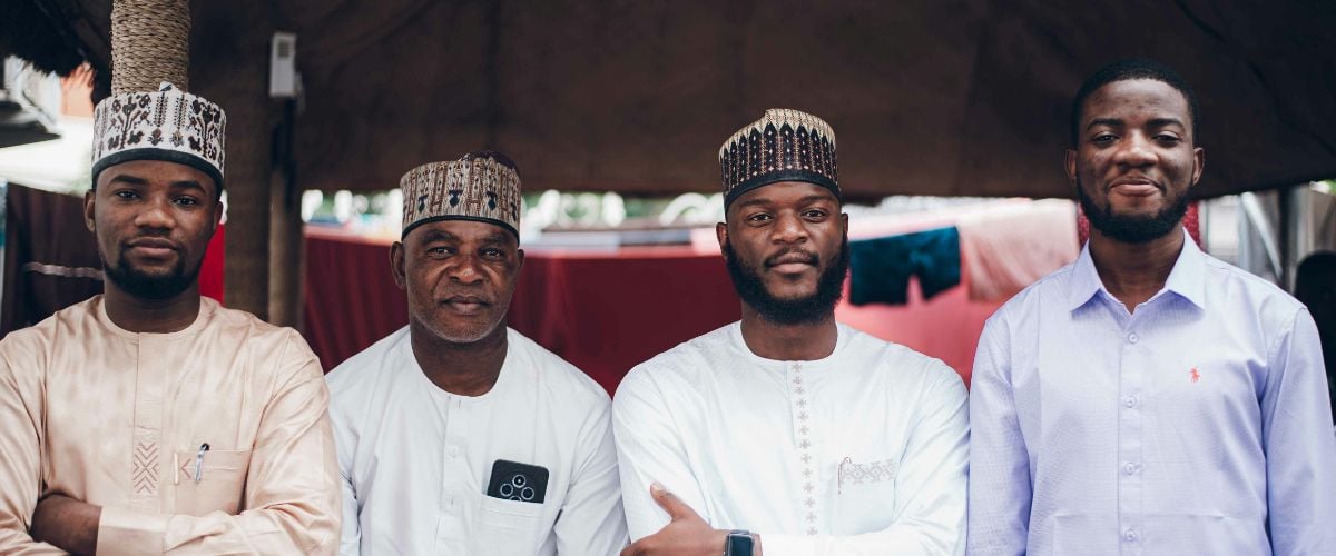 Four Nigerian men stand in a row, looking towards the camera. 