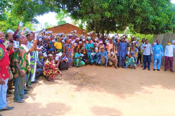 A Group picture of Listeners and community members standing outside holding their newly received radios