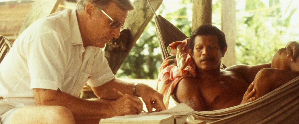 Ivan Schoen sits crouched over a piece of paper with Wayana tribe chief Nwahe lounging in a hammock next to him. The two men worked for decades translating the Bible into the Wayana language. 