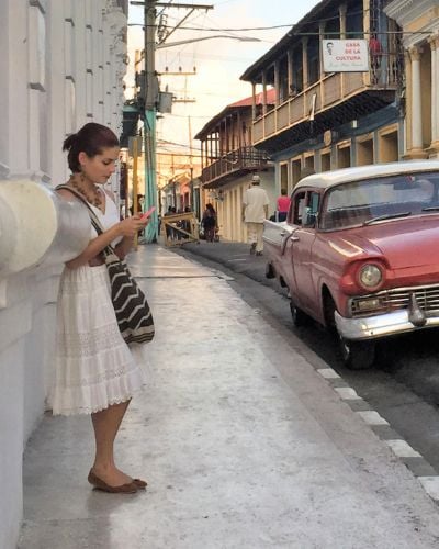 A young women looks down at her phone on the streets of Cuba