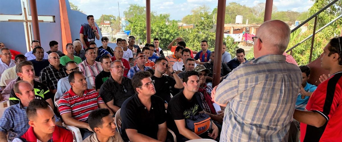 A group of men listen intently at a speaker at a church gathering  in Cuba. 
