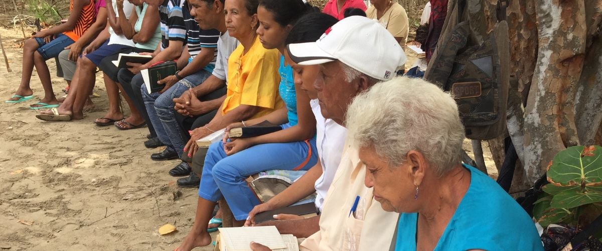 A row of people sit with their bibles open at a church service in Cuba. 