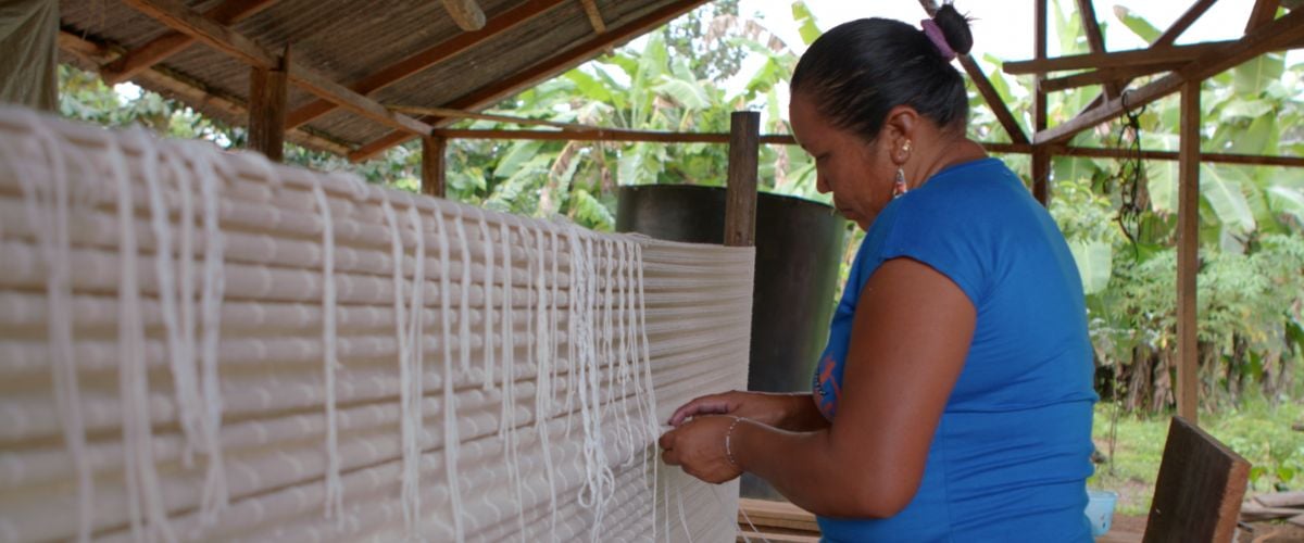 An indigenous woman weaves under a shelter in the jungles of Suriname