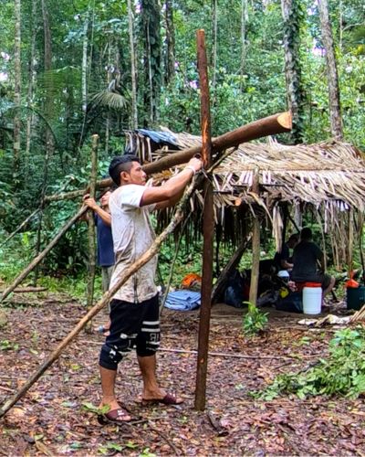 An indigenous man sets up a temporary shelter while traveling through the Amazon jungle in Suriname