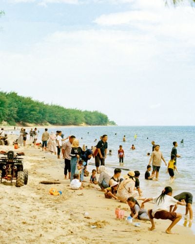 Families and children gather and play on the sands of a beach in Indonesia. 