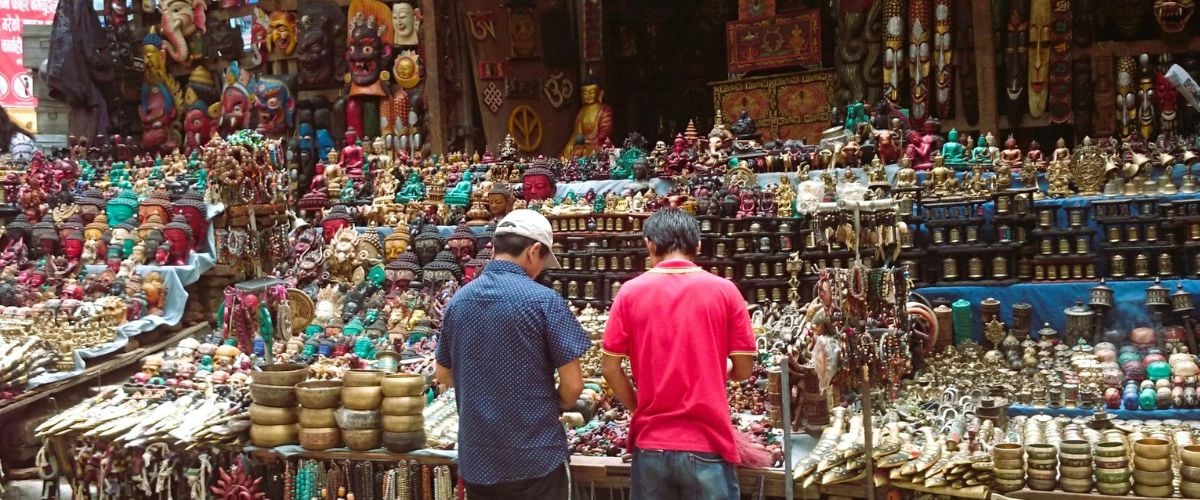 Two men stand before shrine materials in Nepal