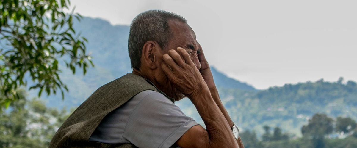 A man in Nepal sits with his head in his hands