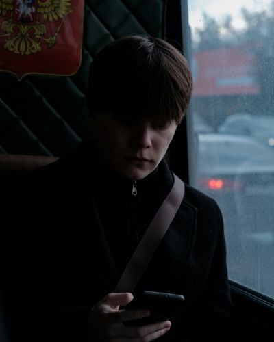 A young man in Russia peers down at his phone.