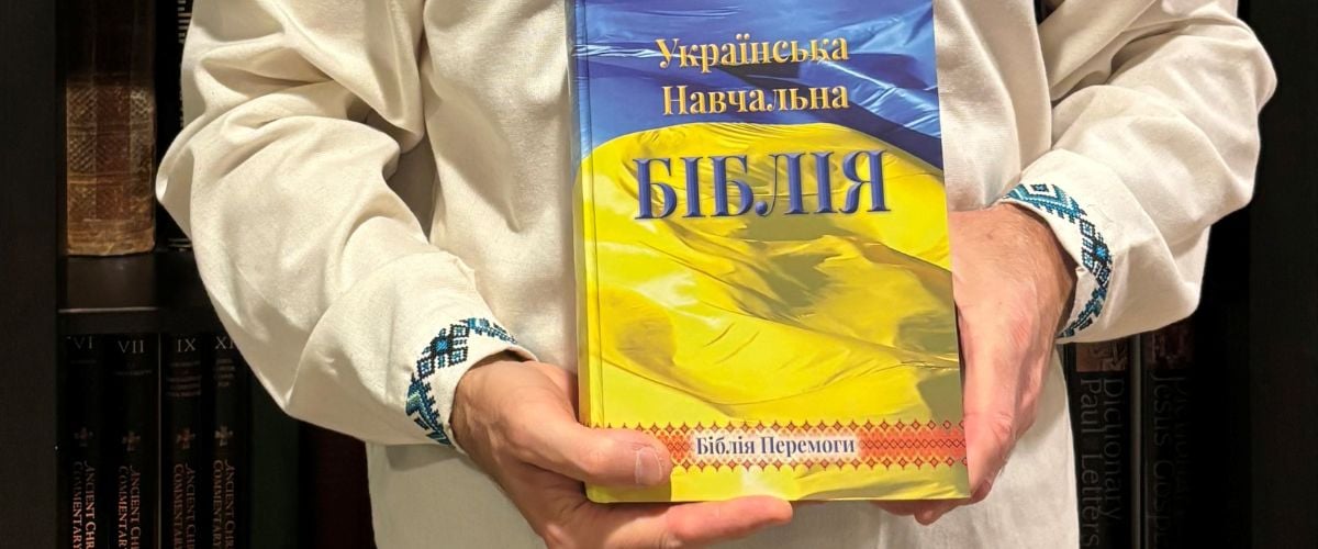 Hands hold a Ukrainian study bible.