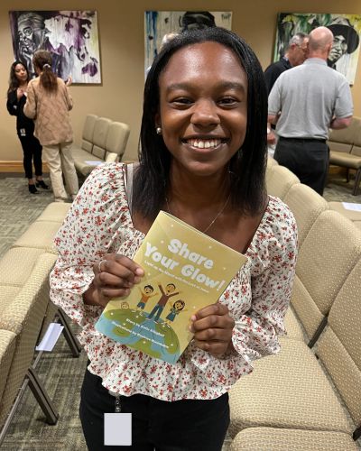 Beatrice poses with a mockup copy of the TWR children's book she illustrated as a part of her internship.