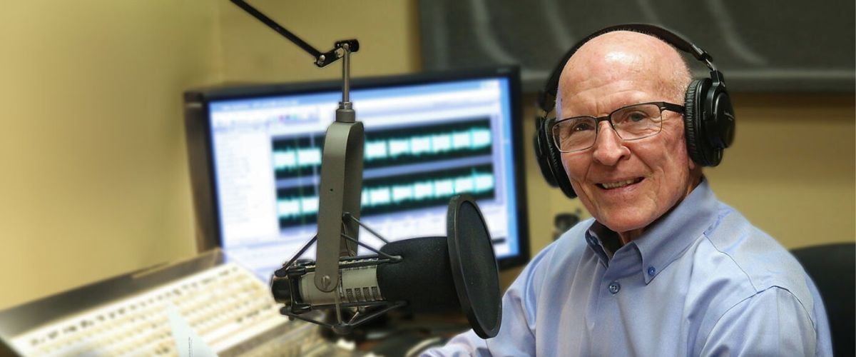 Dr. Harold Sala posed in a studio with headphones on in front of a mic. 