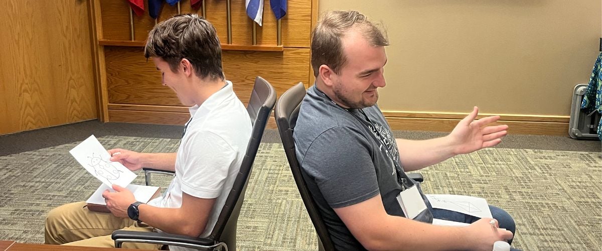 Wade (right) and fellow IT intern, Luka (left), work back-to-back on a communication exercise during intern orientation. 