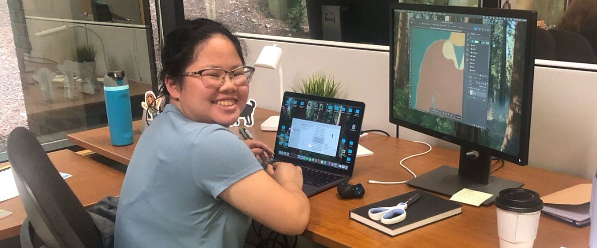 Joanna sits smiling at her desk in the TWR offices in Cary, North Carolina. 