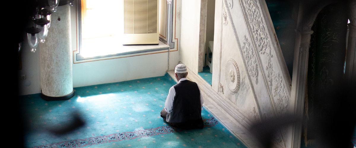 A man prays facing a window in a mosque.