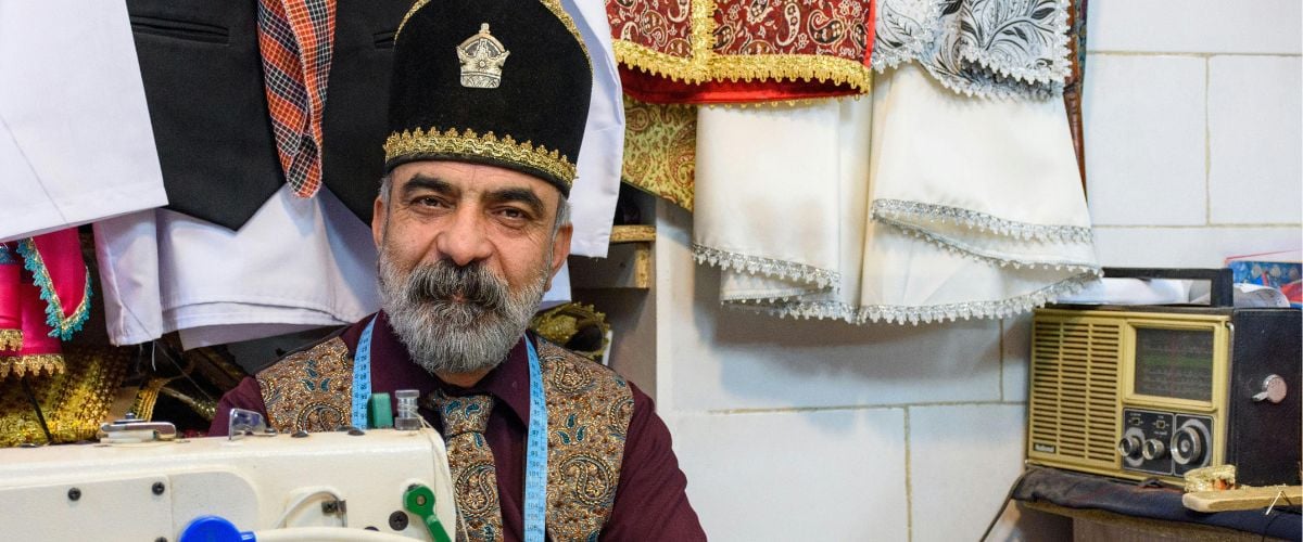 An Iranian man sits by a sewing machine in his shop.