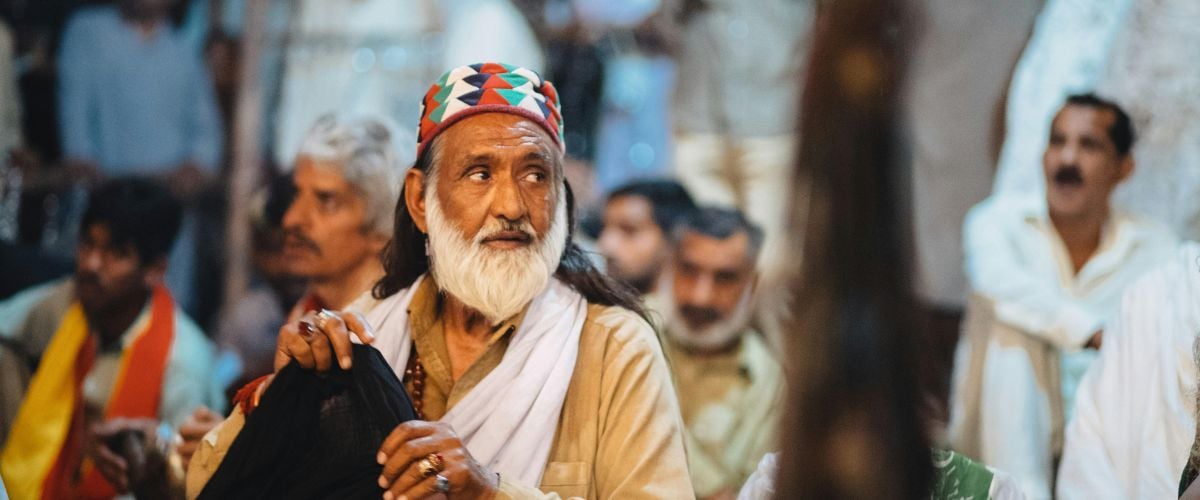 A Pakistani man looks over his shoulder off-camera with a crowd gathered behind him